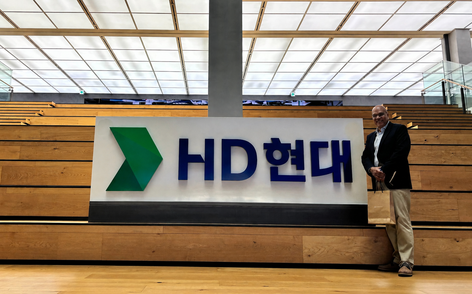 TEXPETROL representative beside the HD Hyundai sign at the company headquarters